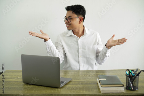 young asian businessman in a workplace holding copyspace with two hands, wearing white shirt with glasses isolated