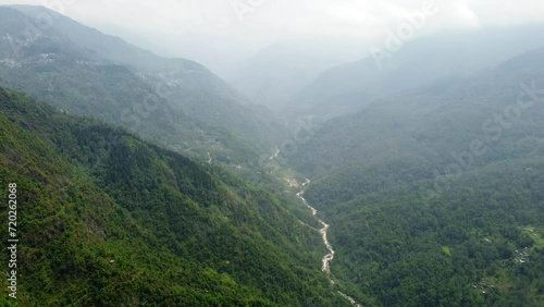 Aerial, tilt down, drone shot, above the tista river, in a valley between mountains and Indian forest, on a sunny day, in sikkim, India photo