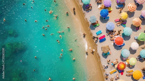A vibrant beach scene from above, packed with people and a wide array of colorful umbrellas.