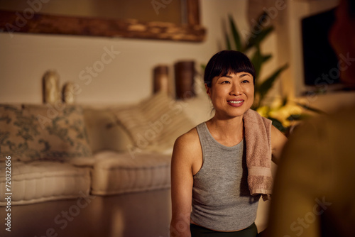 Focus on the smiling Asian female yoga instructor, talking to her client after the class.