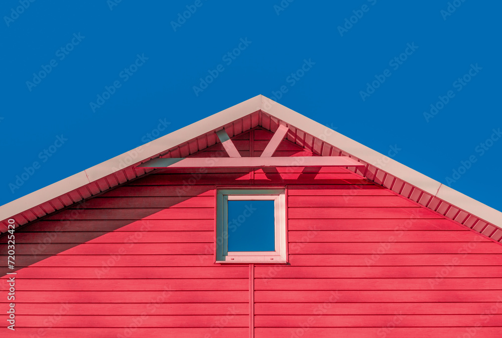 roof of a pink farmhouse wooden house against a blue sky