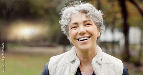 Senior woman with a smile, portrait in the park and happiness in nature, woods or outdoor for a walk in retirement. Happy, face and elderly person with wellness from exercise or healthy workout photo