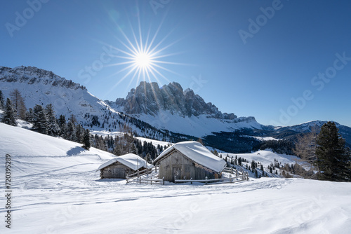 Hütte aus Holz im Schnee im Winter bei Sonne und blauem Hommel in Südtirol in den Dolomiten.