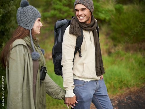 Forest, hiking and happy couple for holding hands, mountain and travel with backpack, nature and bonding. Outdoor, adventure and trekking in path, woods and winter for travelling and explore
