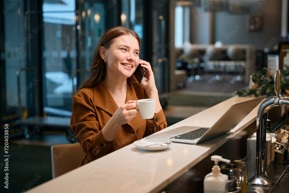 Happy woman talking on phone when drinking coffee Happy woman talking on phone when drinking coffee