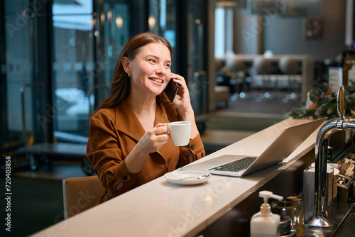 Happy woman talking on phone when drinking coffee