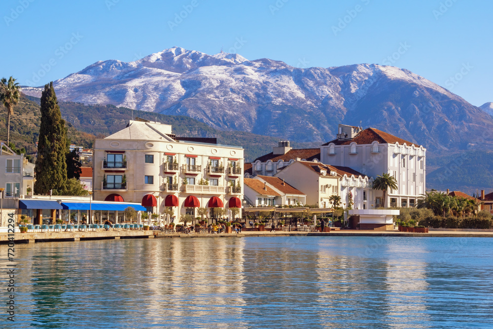 Beautiful winter Mediterranean landscape. Montenegro, Adriatic Sea,  Bay of Kotor. View of embankment of Tivat city  and snow-capped Lovcen mountain