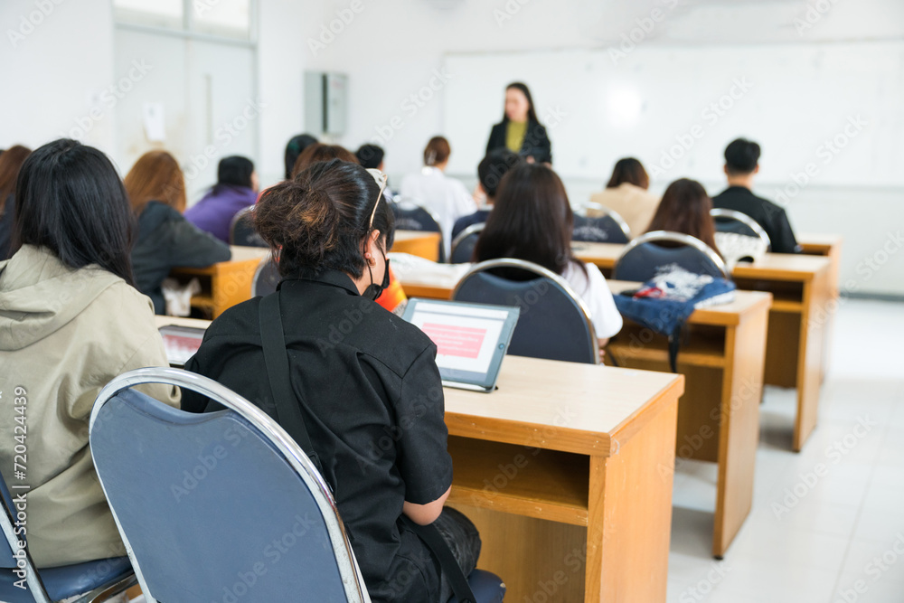 Fototapeta premium Rearview of university students listen to lecturer explaining lesson in the classroom