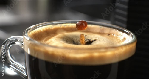 Super slow motion macro of hot creamy aromatic close up coffee  drop is splashing in transparent mug before being served to customer at cafe or bar at 1000 fps. photo