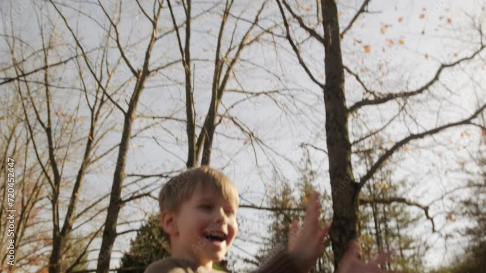 A blond boy cheerfully throws up fallen leaves. A blond boy cheerfully throws up fallen leaves.