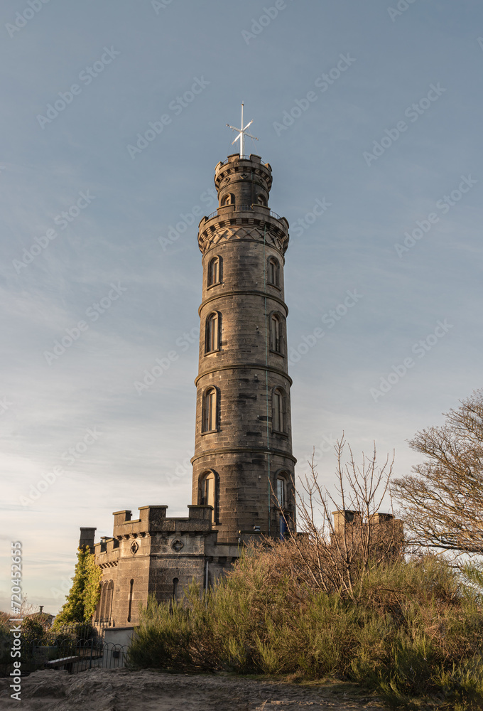 Bottom-up view of Nelson's Monument with a bright blue sky in the background. Architecture design of Tower situated on Calton Hill at Edinburgh, Scotland, Space for text, Selective focus.