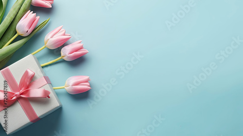 Mother's Day, Top View Photo of Bunch of Pink Tulips Bouquet and Blue Gift Box with Ribbon on Isolated Pastel Blue Background