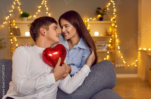 Happy young people love expression close in hug with heart balloon, showing romantic moment feelings. Valentine day emotion, loving male female couple celebrate holiday, studio garland interior design