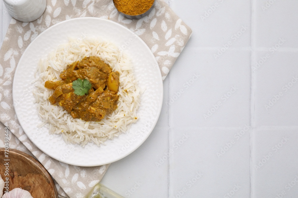 Delicious chicken curry with rice and ingredients on white tiled table, flat lay. Space for text