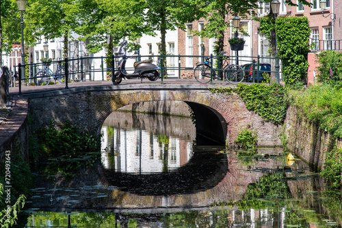 Close up view of bridge and street on Havik canal in Amersfoort, the Netherlands, lined with historic buildings and scooter and bicycles parked on bridge photo
