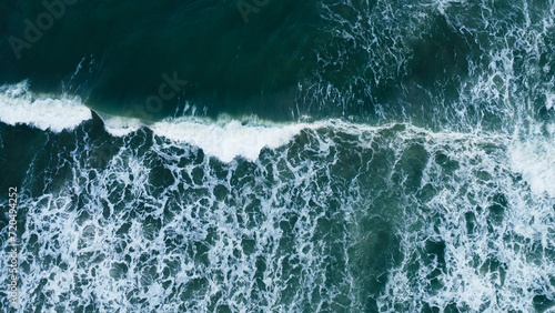 Overhead view to blue stormy ocean waves with white foam.