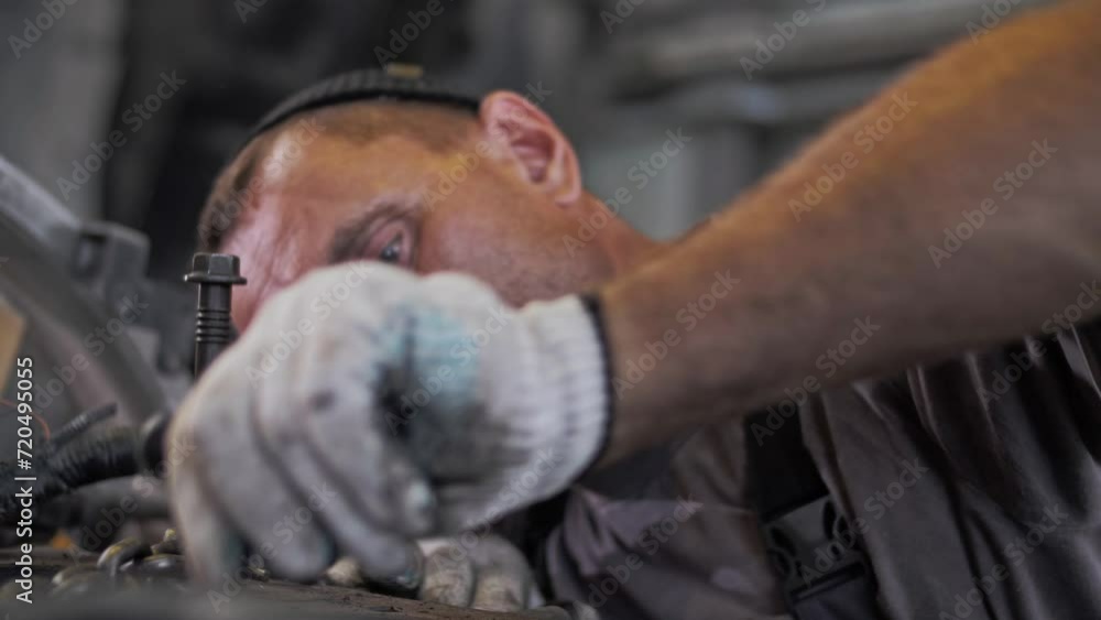 Focused automotive engineer performs maintenance and overhaul of a large gasoline engine Focused automotive engineer performs maintenance and overhaul of a large gasoline engine