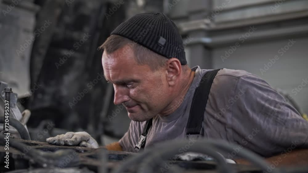 Professional engine mechanic inspects a huge diesel truck engine for examples of breakdowns Professional engine mechanic inspects a huge diesel truck engine for examples of breakdowns