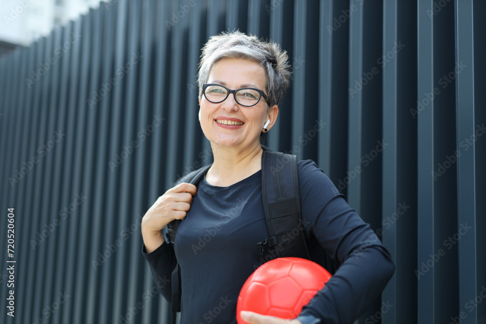Happy woman in sportswear with ball, emphasizing vitality and effort in a outdoor setting. Happy woman in sportswear with ball, emphasizing vitality and effort in a outdoor setting.