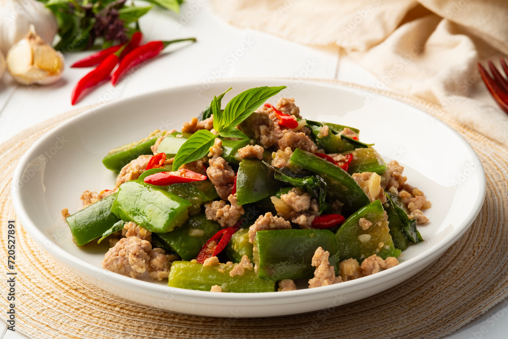 Stir fried Long Eggplant with minced pork and chili basil in white plate
