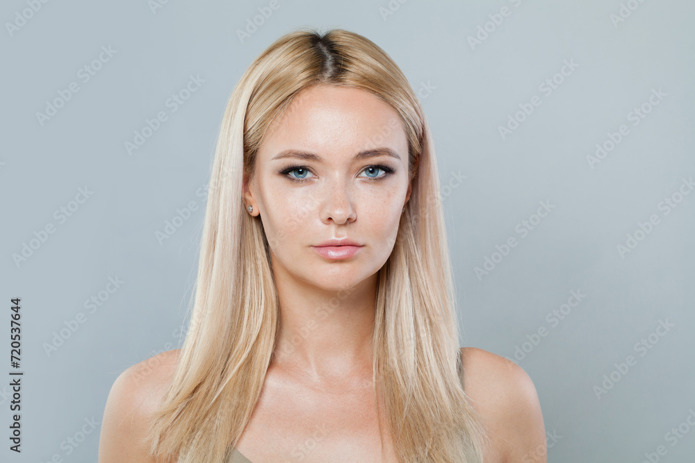 Glamorous blonde woman with long straight hair and clean fresh pure perfect skin isolated on gray background, studio portrait Glamorous blonde woman with long straight hair and clean fresh pure perfect skin isolated on gray background, studio portrait