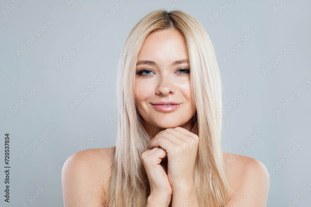 Lovely smiling joyfully female model with fair hair looking at camera, being happy. Studio shot of good-looking beautiful woman with pure shiny skin and blonde hair on gray background Lovely smiling joyfully female model with fair hair looking at camera, being happy. Studio shot of good-looking beautiful woman with pure shiny skin and blonde hair on gray background