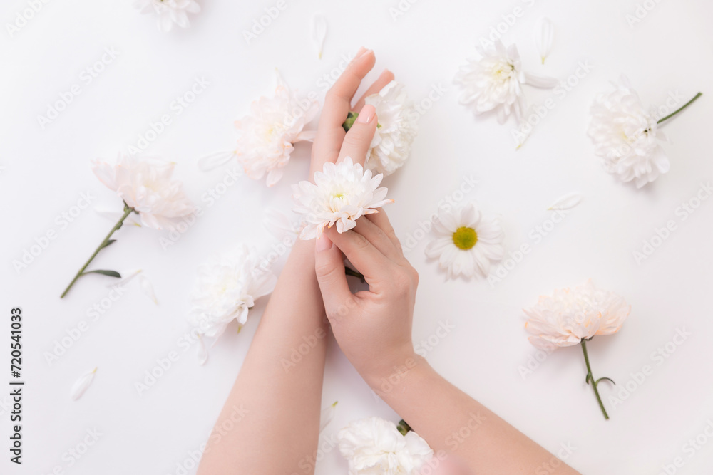 Closeup beautiful sophisticated female hands with pink flowers on white background. Concept hand care, antiwrinkles, antiaging cream, spa Closeup beautiful sophisticated female hands with pink flowers on white background. Concept hand care, antiwrinkles, antiaging cream, spa