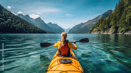 Person kayaking in a vibrant mountain lake surrounded by lush forests and majestic peaks on a sunny day.