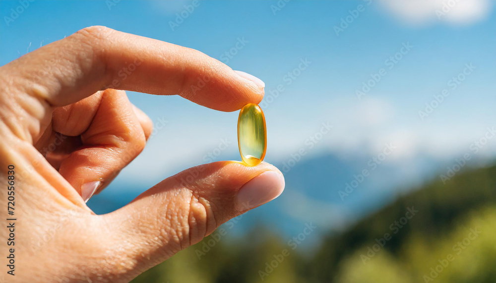 Female hand holding a small yellow capsule of nutritional supplement . Food supplement, vitamin D, omega, vitamin C, multivitamins Female hand holding a small yellow capsule of nutritional supplement . Food supplement, vitamin D, omega, vitamin C, multivitamins