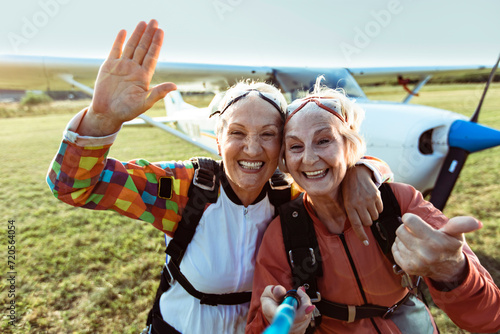 Two smiling senior women taking selfie before skydiving photo