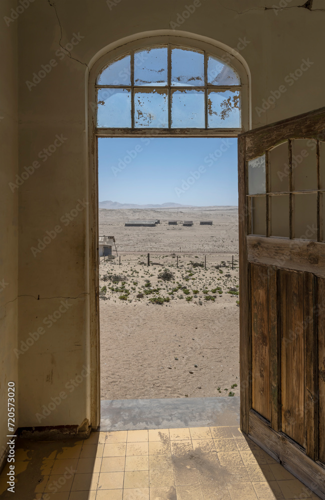desert view through forsaken hospital door at mining ghost town in desert, Kolmanskop, Namibia desert view through forsaken hospital door at mining ghost town in desert, Kolmanskop, Namibia