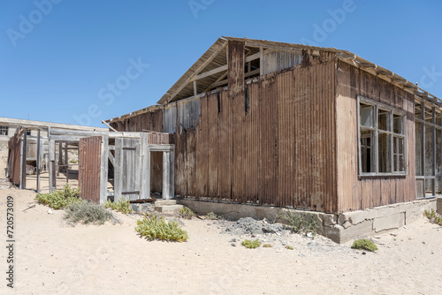 forsaken corrugated-iron building on sand at mining ghost town in desert, Kolmanskop, Namibia