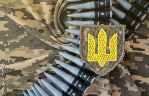 Ukrainian army symbol on machine gun belt lies on ukrainian pixeled military camouflage close up photo