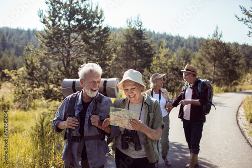 Group of senior hikers with backpacks and map enjoying nature trail
