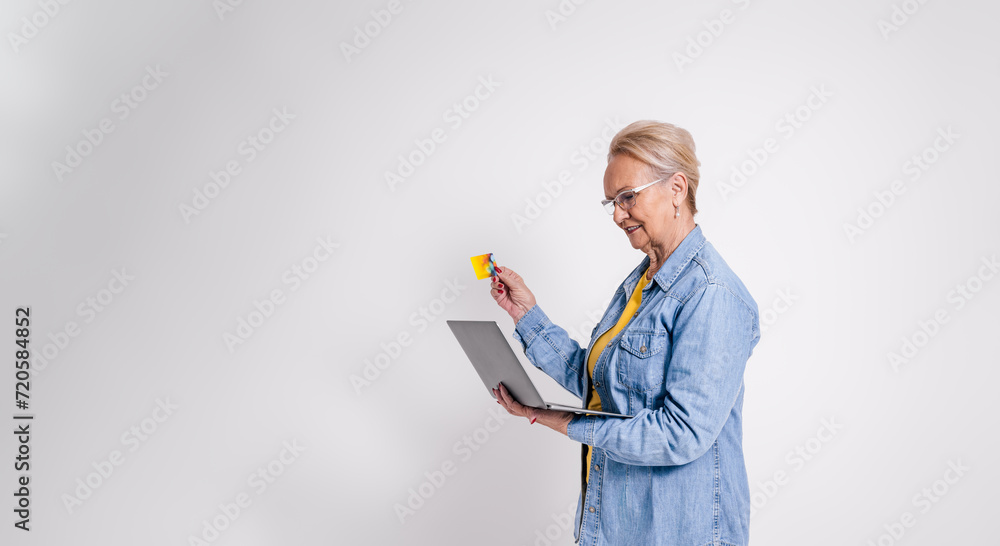 Side view of senior manger with credit card and laptop working while standing on white background Side view of senior manger with credit card and laptop working while standing on white background