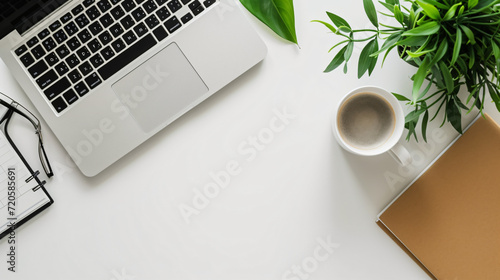 A home office flat lay with a laptop planner stylish desk accessories a houseplant and coffee mug set on a minimalist clean desk.