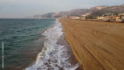 Long, sandy Castelldefels Beach in Barcelona, waves gently lapping the shore, aerial view