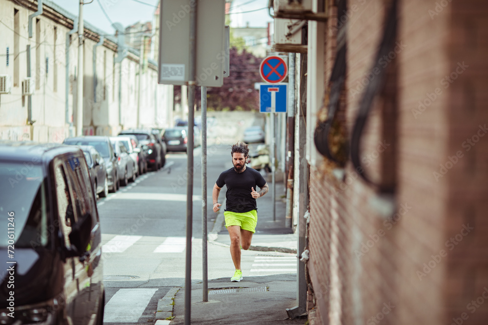 Man jogging in city street wearing neon shorts