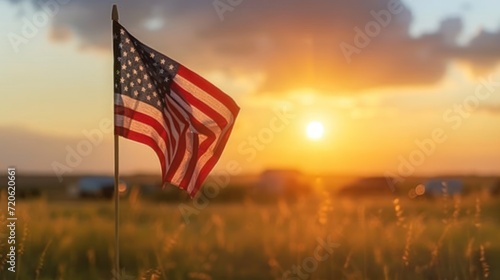  an american flag blowing in the wind in a field of tall grass with the sun setting in the background and clouds in the sky with a few clouds in the foreground. photo