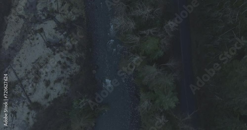 Ungraded 4k high-angle aerial drone footage of a rural mountain road alongside a river on a dark winter morning in Washington State. photo
