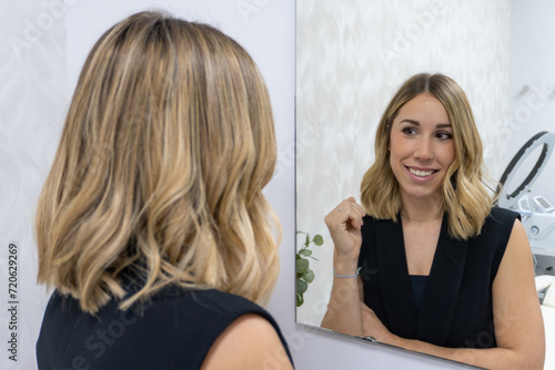 young enterprising woman smiles looking at herself in the mirror