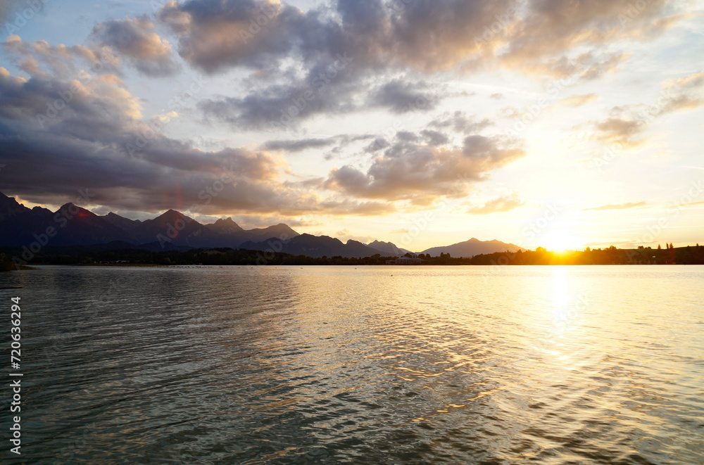 calm and peaceful Forggensee lake in the Bavarian Alps at romatic sunset on a sunny September evening