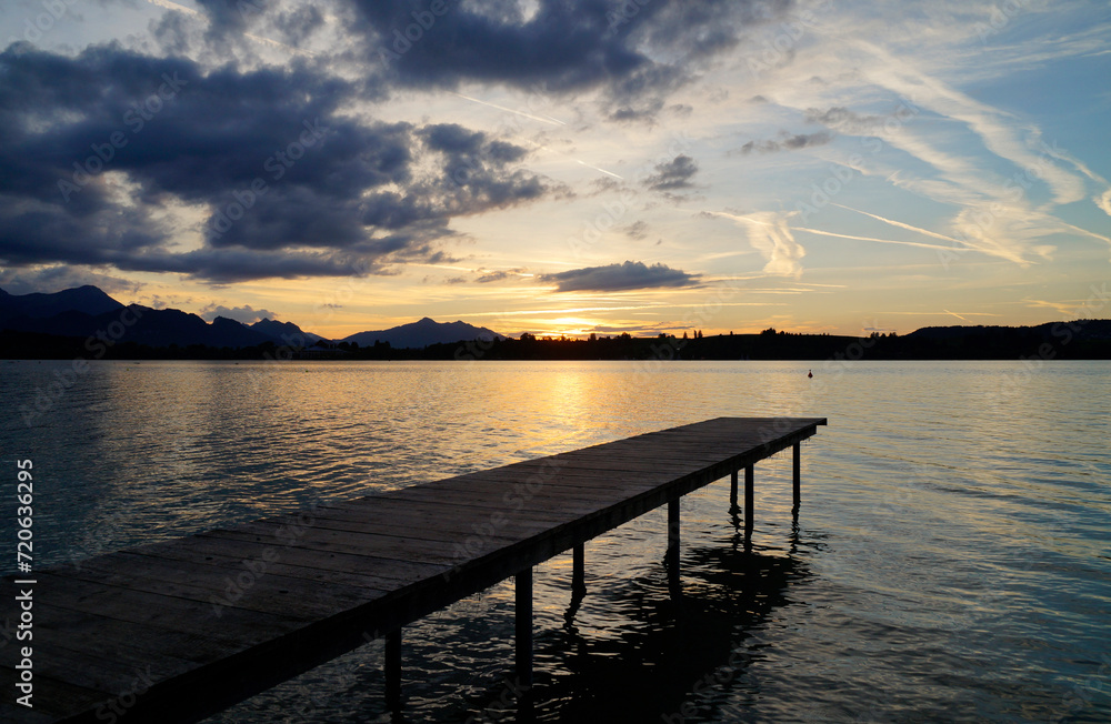 a long pier at alpine lake Forggensee in the Bavarian Alps at romatic sunset on a sunny September evening	
