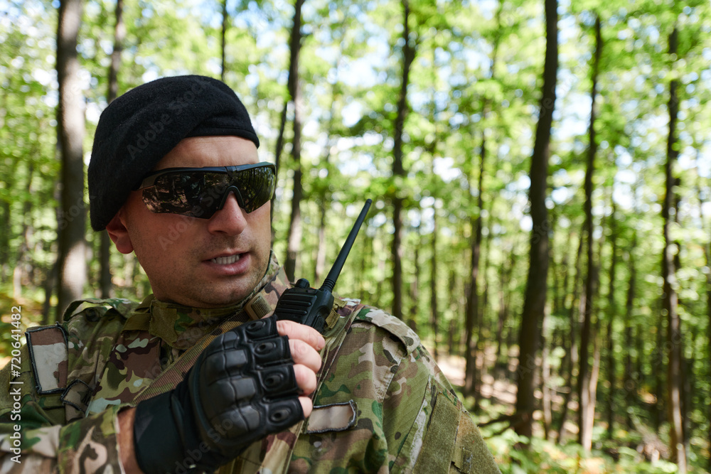 A military major employs a Motorola radio for seamless communication with his fellow soldiers during a tactical operation, showcasing professionalism and strategic coordination