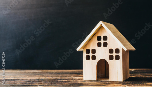 Tiny wooden house on black background, copyspace on a side