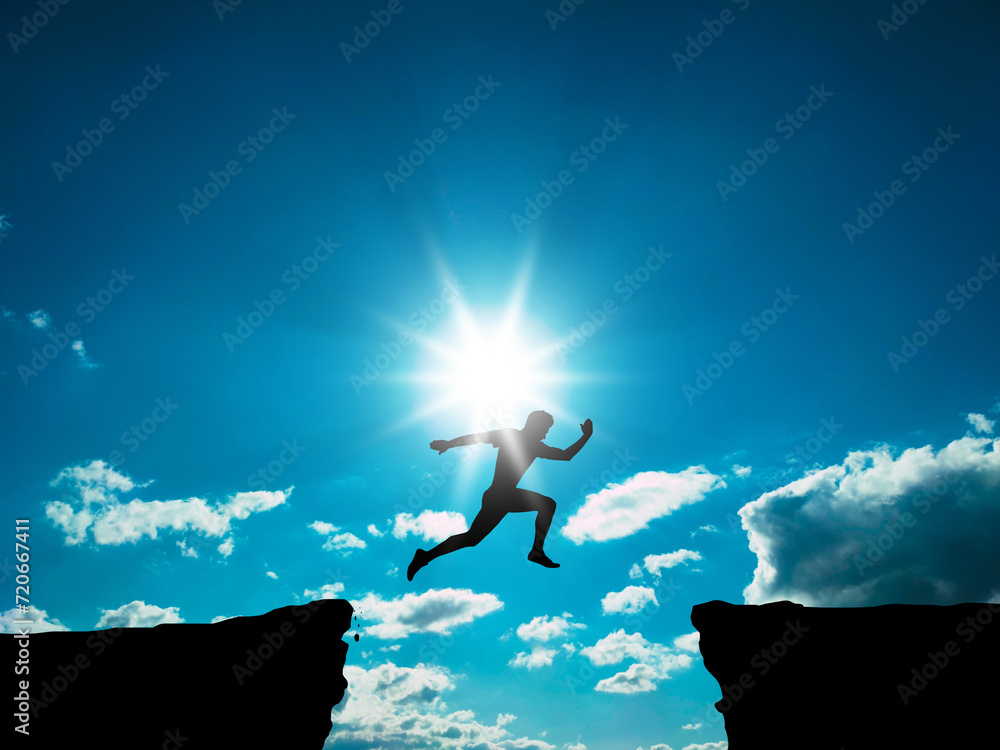 A man jumps over a gorge against a sky with clouds. Success concept.