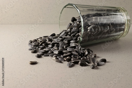 Fotografie Overturned glass beaker with sunflower seeds.