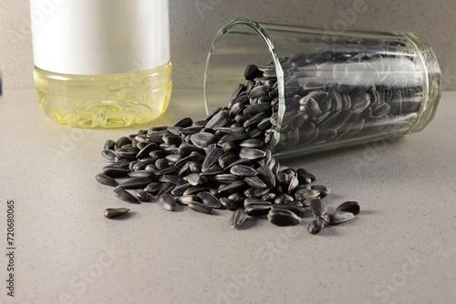 Fotografie There are sunflower seeds in an overturned glass, next to a bottle with sunflower oil and a readable label