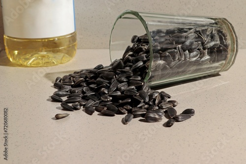 Obraz na plátně There are sunflower seeds in an overturned glass, next to a bottle with sunflower oil and a readable label