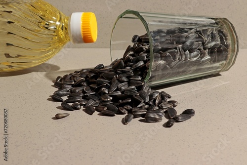 Obraz na plátně There are sunflower seeds in an overturned glass, next to a bottle of sunflower oil